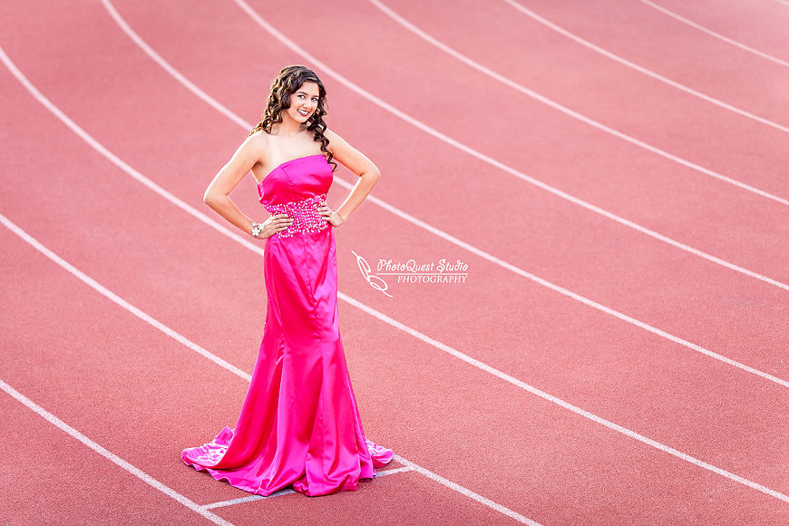High School Senior photos session of beautiful Latina Teen from Menifee, California - Miss Isabel Donadio.  Location: Paloma Valley High School, Menifee, CA.  Photography: PhotoQuest Studio - Menifee Wedding, Family and Event Photographer, standing on the track