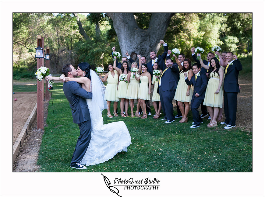 Temecula Creek Inn Wedding Photo by Temecula Wedding Photographers - bride and groom kissing while their bridal party cheering