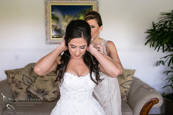mom putting on necklace for the bride