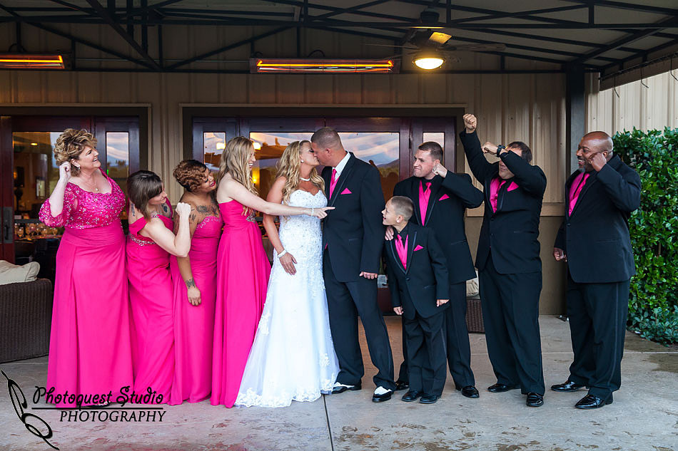 bride and groom kissing and the bridal party cheering at Wiens family cellars temecula winery by temcula wedding photographer