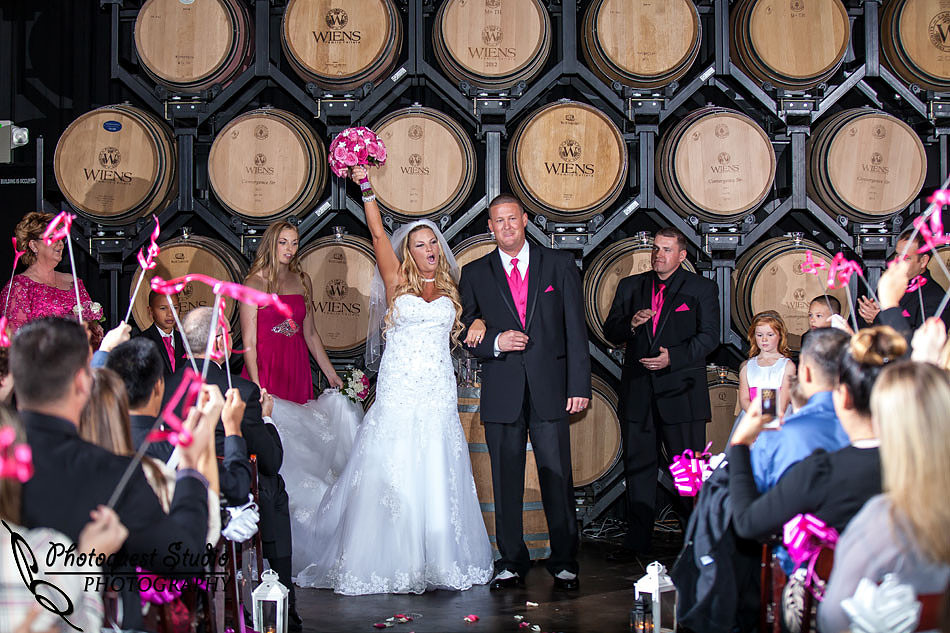 the bride cheering at barrel room wedding ceremony at Wiens family cellars temecula winery by temcula wedding photographer