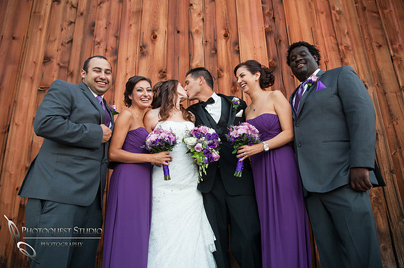 bride and groom kissing and the bridal party cheering at Falkner winery wine wedding by temecula wedding photographer