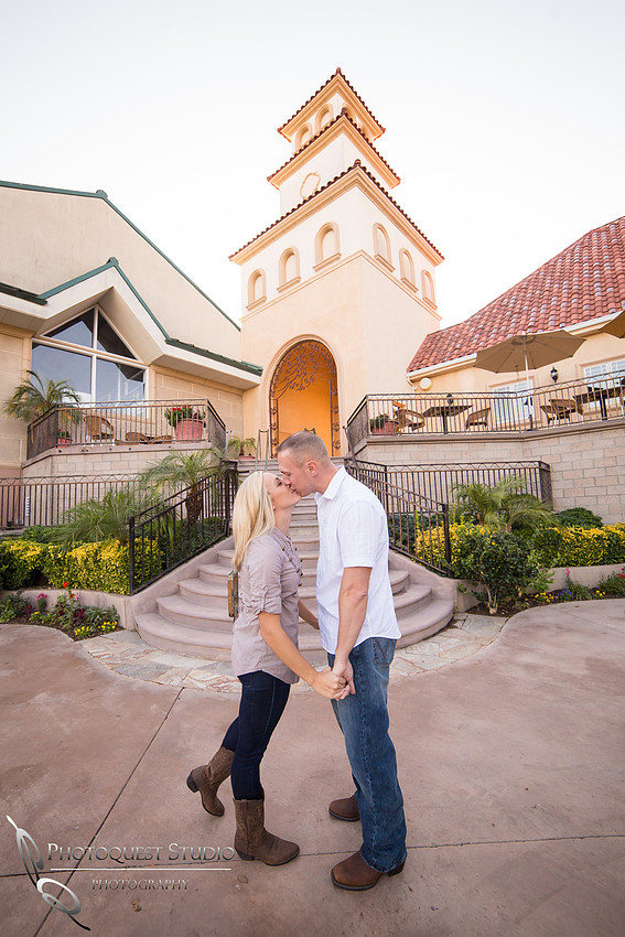 Couple kissing by the clock tower at Engagement photo at South Coast Winery, California by Temecula Wedding Photographers